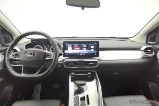 Салон Geely Coolray: панель приборов и большой центральный экран мультимедиа, вид на руль и центральную консоль в студийном освещении.