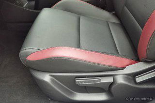 Крупный план сиденья Geely Coolray с комбинированной кожаной/тканевой обивкой и вставками красного цвета; видны регулировки сиденья и швы.