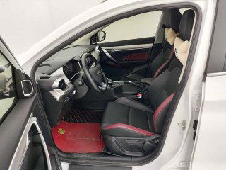Передние сиденья GEELY COOLRAY с комбинированной обивкой и красными акцентами, вид с открытой водительской двери, показана отделка салона.