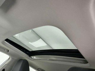 Панорамный люк GEELY COOLRAY — крупный план открытого стеклянного люка на крыше и внутренняя отделка потолка салона автомобиля.