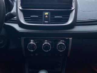 Крупный план центральной консоли Toyota Yaris L с семью управлениями климат-контроля и дисплеем над панелью приборов.