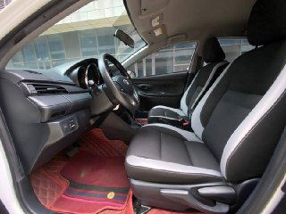 Водительское место Toyota Yaris L: боковой профиль сиденья, рулевая колонка и пространство для ног, состояние обивки видно подробно.