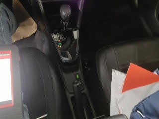 Крупный план селектора передач и пространства между передними сиденьями Toyota Yaris L 2022, видны элементы обшивки и документы на пассажирском сиденье.