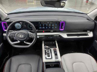 Панорамный вид салона Hyundai Mufasa: рулевое колесо, цифровая приборная панель и большой горизонтальный экран мультимедиа в интерьере.