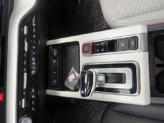 Ближний план центральной консоли и селектора передач Hyundai Mufasa: кнопки управления, ниша для мелочей и отделка вокруг рычага АКПП.