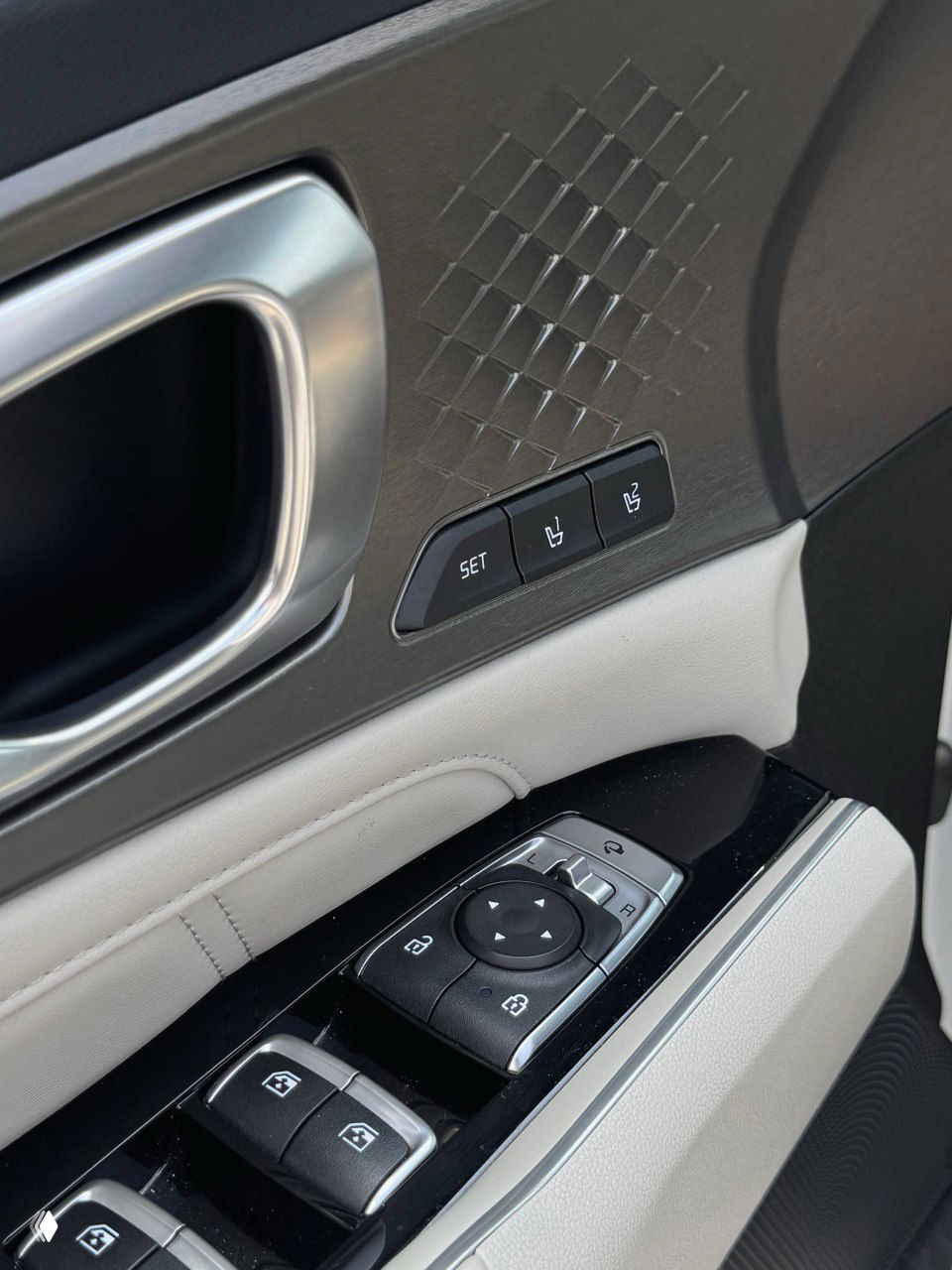 Крупный план панели дверного подлокотника с блоком управления стеклоподъемниками и кнопками памяти сиденья в KIA Sorento.