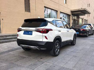 Вид сзади белого KIA KX3 на парковке: багажник, задние фонари, диффузор и линия крыши автомобиля в городском окружении