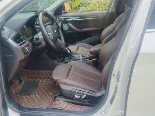 Переднее пассажирское место BMW X1 xDrive 25Li 2021 — коричневые сиденья, боковая панель двери и часть приборной панели, интерьер в хорошем состоянии.