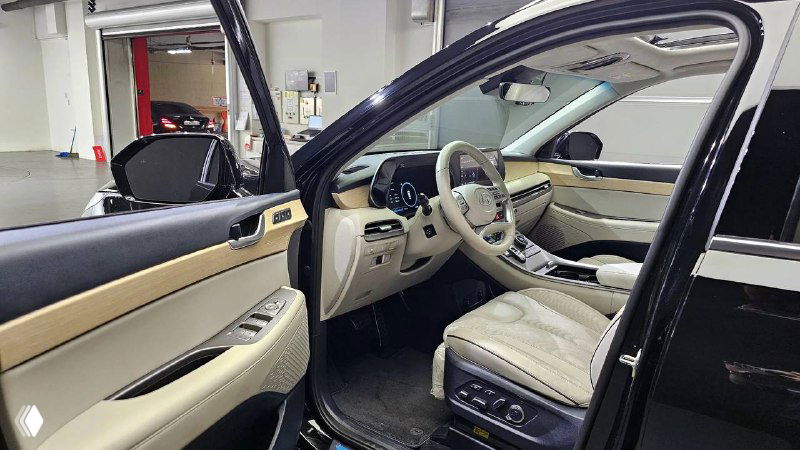 Открытая передняя дверь и вид на водительское место Hyundai Palisade 2022 — показывается пространство входа, сиденья и панель приборов сбоку.