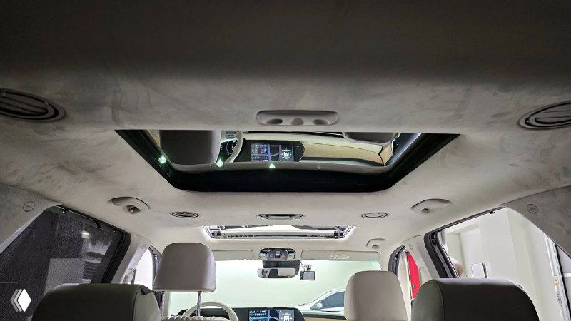 Панорамный люк в потолке салона Hyundai Palisade 2022 — вид внутрь с подголовниками и отражением стеклянного люка, подчёркивающий световой профиль салона.