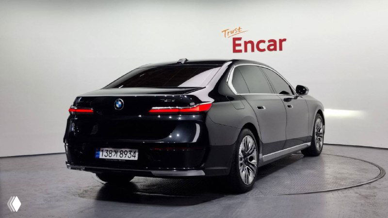 Чёрный BMW 740d xDrive — вид сзади-вел; фотография показывает заднюю часть кузова и световые элементы в выставочном пространстве Encar.