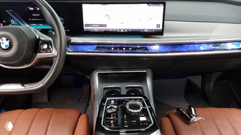Центральная консоль BMW 740d — вид сверху на селектор, сенсорные элементы и мультимедийный экран, коричневые кресла видны по бокам.