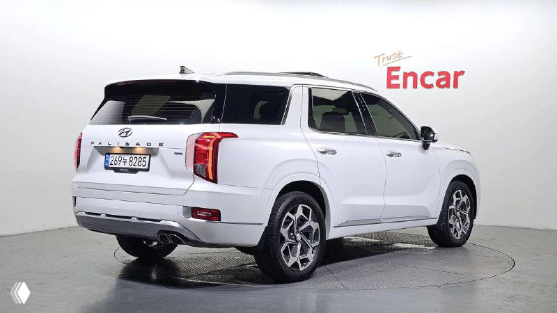 Белый Hyundai Palisade, вид сзади и в повороте в студийной обстановке; демонстрация задней части кузова и светотехники для объявления.