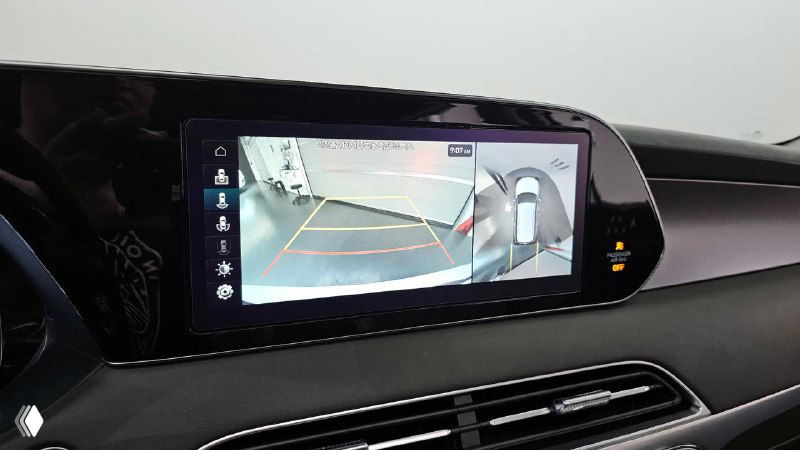 Экран мультимедиа и изображение с камеры заднего вида на мониторе автомобиля; показана парковочная разметка и интерфейс.