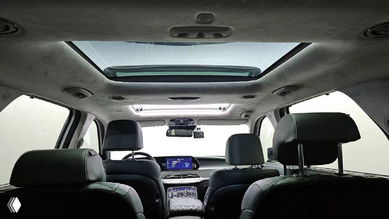 Вид на салон с задней части салона: панорамный люк, потолочные консоли и обзор фронтальной части салона с рядами сидений.