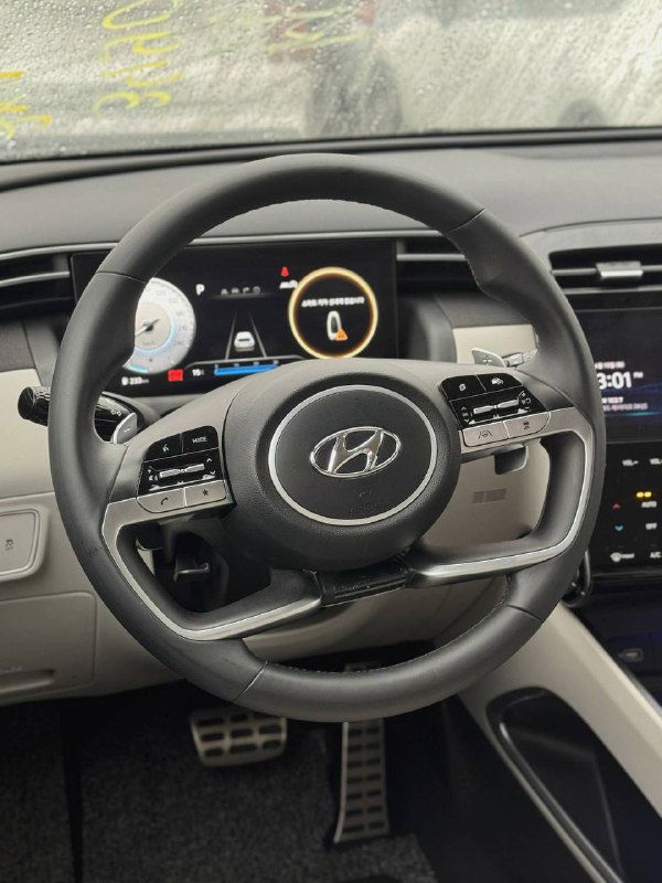 Фотография рулевого колеса и передней панели салона Hyundai Tucson: мультируль с кнопками управления, часть приборной панели и интерьерная отделка.