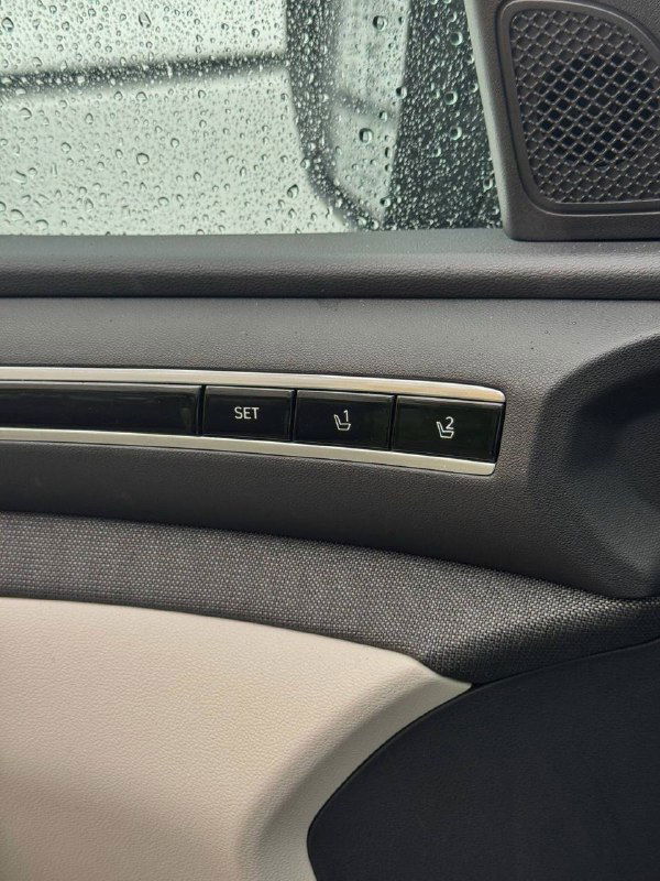 Крупный план внутренней ручки двери и панели с кнопками памяти сиденья в Hyundai Tucson: текстильная отделка и элементы управления рядом с окном.