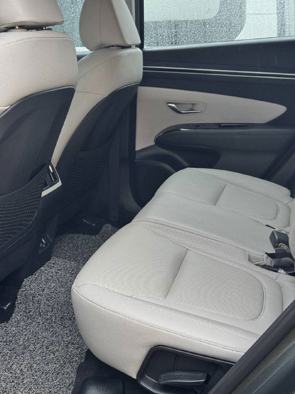 Фотография заднего ряда сидений Hyundai Tucson: светлая тканевая обивка, простор для пассажиров и вид с дверного проёма на задний ряд.