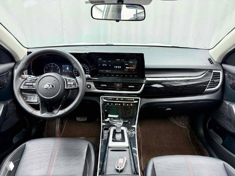Салон KIA KX3: панель приборов, мультимедийный экран и центральная консоль с селектором КПП и кнопками управления.
