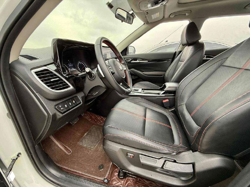 Передние сиденья KIA KX3 в кожзаменителе с контрастной красной прострочкой, вид по диагонали на водительское и пассажирское кресла.