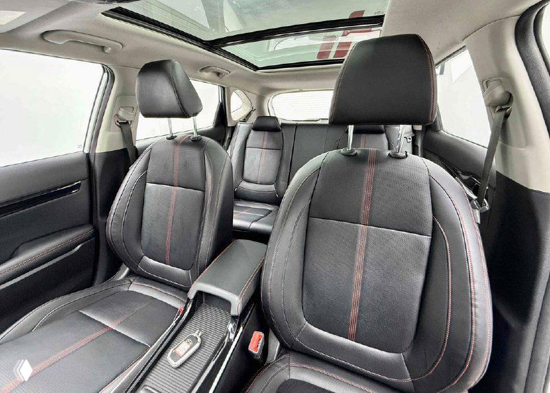 Вид с переднего пассажирского места на передний ряд: кресла, центральный подлокотник и панорамный люк над салоном.