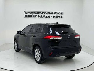 Задняя трёхчетвертная проекция чёрного Toyota Corolla Cross в белой фотозоне — видны фонари, багажная дверь и общий профиль кузова.