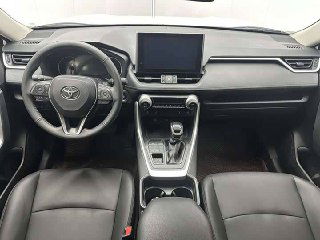 Интерьер Toyota RAV4: торпедо с крупным сенсорным дисплеем, рулевое колесо, центральная консоль с селектором вариатора и передние кожаные сиденья в салоне.