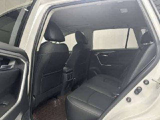 Вид на задние сиденья Toyota RAV4: кожаная обивка, место для ног, задняя часть передних сидений и дверной проем — пространство салона для пассажиров.