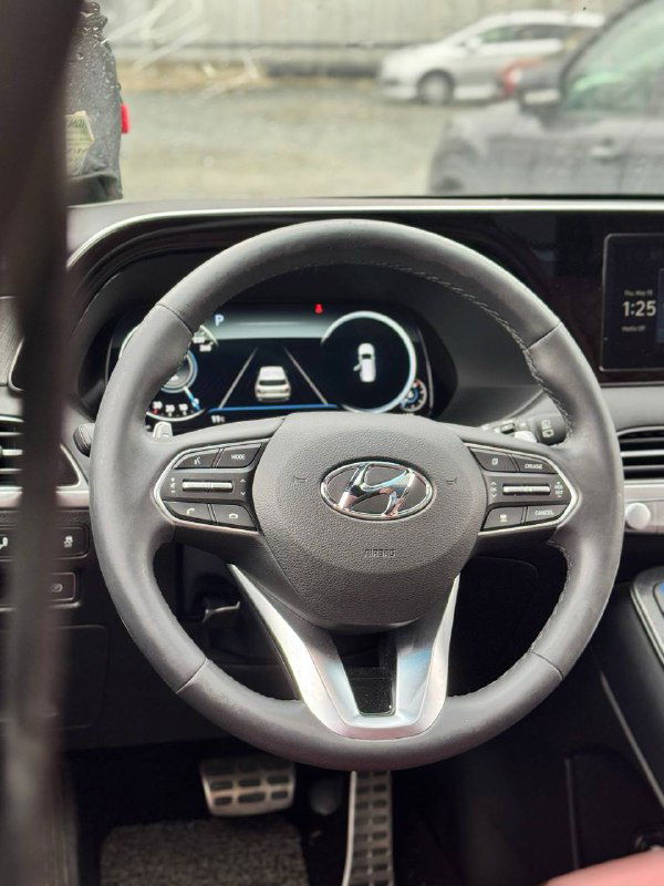 Рулевое колесо и цифровая приборная панель Hyundai Palisade, детальный кадр салона с элементами управления на руле и экраном бортового компьютера.
