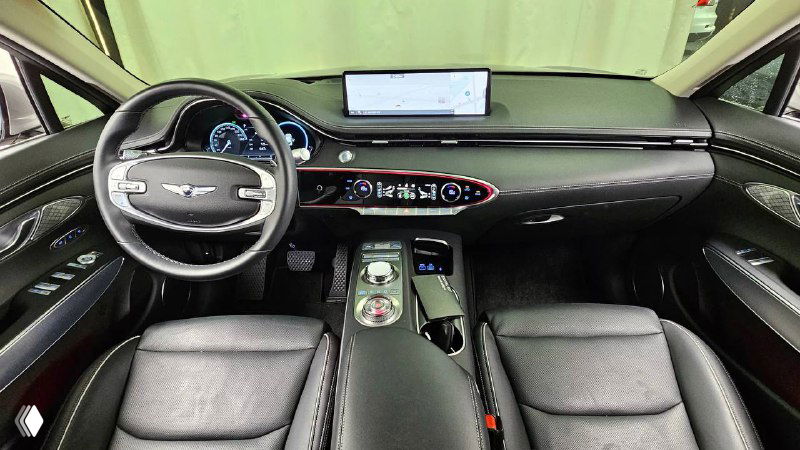 Интерьер второго автомобиля Genesis GV70 2022 с тёмной кожей: торпедо, большой экран мультимедиа и центральный тоннель с рычагом переключения.