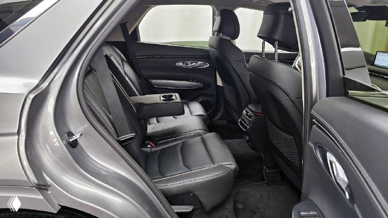 Вид заднего сиденья и центрального подлокотника Genesis GV70 2022 в тёмной отделке: комфортная посадка, подстаканники и детали обивки.