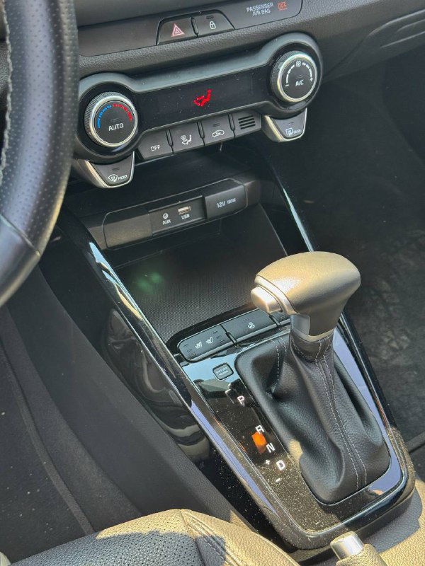 Ближний план селектора коробки передач и центрального тоннеля KIA Stonic с видимыми кнопками и отделкой вокруг рычага