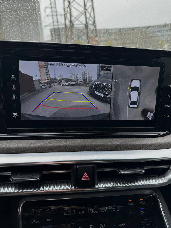 Экран мультимедиа KIA K5 с изображением с камеры заднего вида и разметкой парковки, демонстрирует систему помощи при маневрировании и обзор сзади.