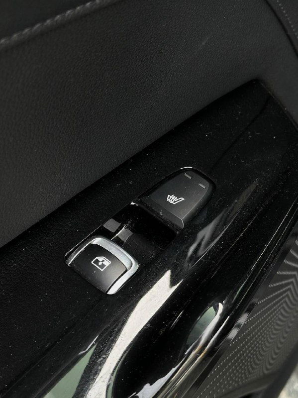 Кнопки на дверной панели KIA K5 для регулировки стеклоподъёмников и подогрева, крупный план элементов управления и декоративной отделки на двери.