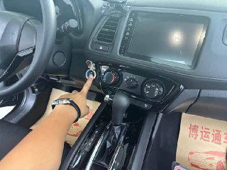 Центральная панель Honda Vezel 2022: мультимедийный экран, блок климат-контроля и селектор передач; на фото видно руку человека, указывающего на зажигание.