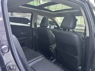 Задний ряд сидений и панорамный люк Honda Vezel 2022: чёрная обивка, подголовники и достаточное пространство для пассажиров, фото сделано с открытой двери.