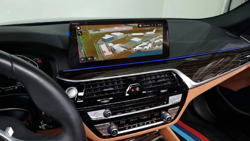 Крупный дисплей мультимедиа BMW показывает навигационную карту; видно центральную панель управления, декоративную подсветку и воздуховоды.