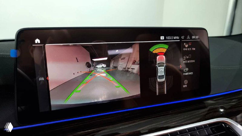 Экран с изображением камеры заднего вида BMW и траекторией парковки на мониторе, демонстрация ассистента парковки и сенсоров.