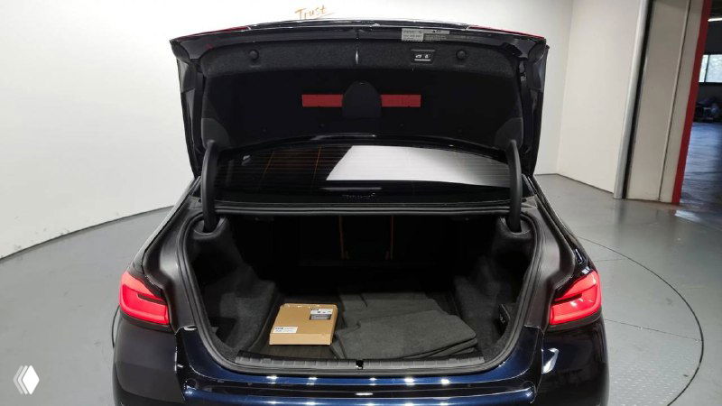 Открытый багажник BMW 520i с видом на грузовое отделение, в багажнике видна коробка, ровный пол и обшивка багажника.