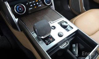 Крупный план центральной консоли Range Rover: селектор коробки, органы управления и отделка под дерево — фото деталей интерьера для покупателей.