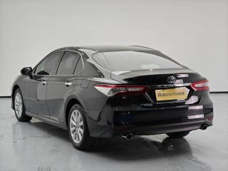 Вид сзади чёрной Toyota Camry 2020 в студии, показаны задние фонари, бампер и багажник, фото подтверждает отсутствие окрасов и общий внешний вид.
