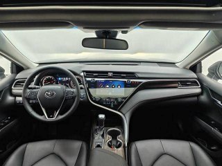 Интерьер Toyota Camry 2020: панорамный снимок приборной панели, мультимедиа-экран, руль и передние кресла, демонстрируется состояние салона для покупателя.