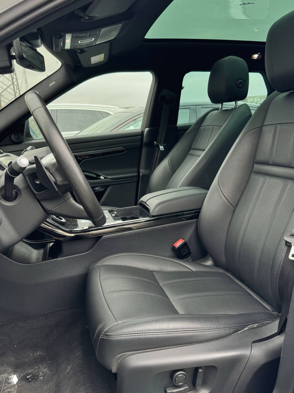 Ещё один крупный план селектора передач и управления климатом на глянцевой панели Range Rover Evoque, видно поворотные регуляторы и надпись Land Rover.