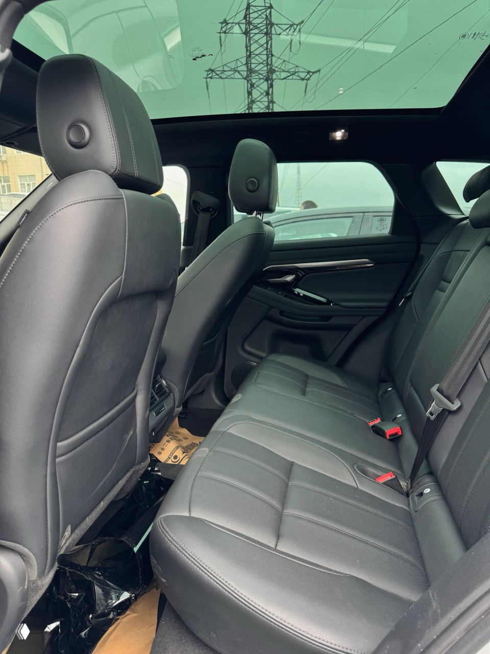 Широкий вид водительской части салона Range Rover Evoque: руль, панель, центральная консоль и педали — чистый аккуратный интерьер.