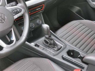 Крупный план центральной консоли Volkswagen Lavida: селектор передач, карман под подлокотником и кнопки управления климатом внутри салона.