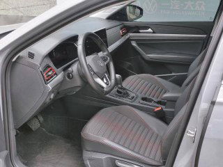 Вид с открытой дверью на водительское сиденье Volkswagen Lavida: руль, кресло с декоративной прострочкой и дверная панель с ручкой и кнопками.