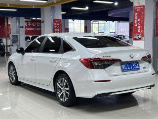 Белый Honda Civic 2022, вид сзади и боковой ракурс в крытом выставочном зале, видны задние фонари и дизайн багажника.