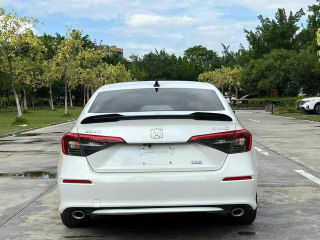 Вид сзади на Honda Civic 2022 — внешний вид багажника и задней оптики без номерного знака, фото сделано на открытой стоянке.