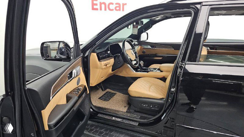 Открытая передняя дверь KIA Mohave с видом на водительское место и порог: бежевые кожаные сиденья и пространство у входа в салон.