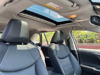 Салон второго Toyota RAV4 2021 с панорамной крышей: передние кресла, отделка потолка и открытый люк, вид сверху на интерьер.